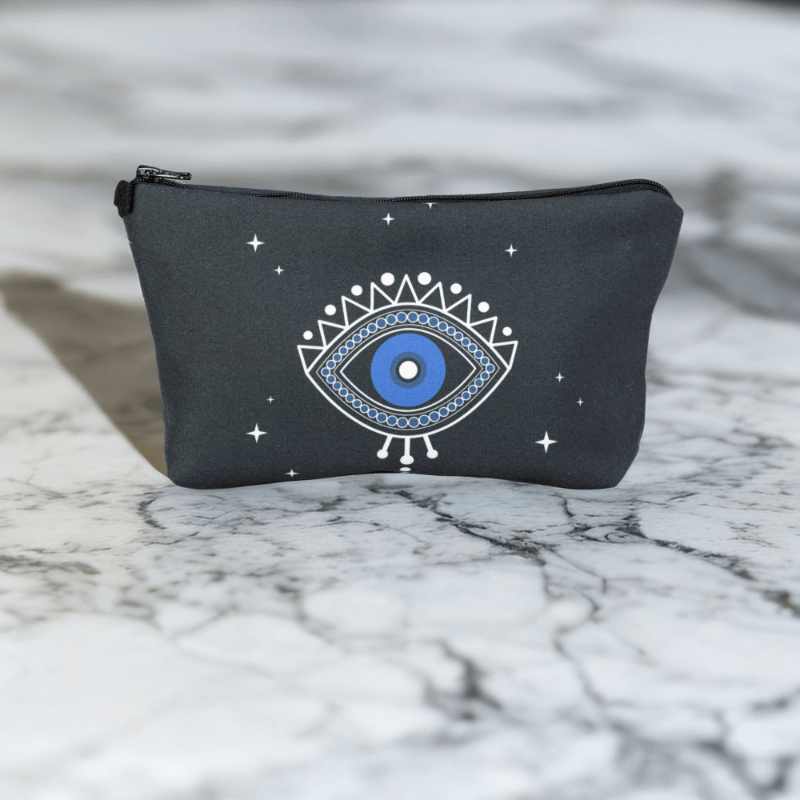 A black star bag with blue evil eye styling sitting on a marble top.