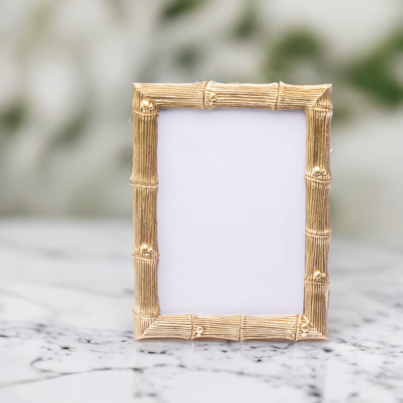 A gold bamboo wedding photo frame on a marble top.