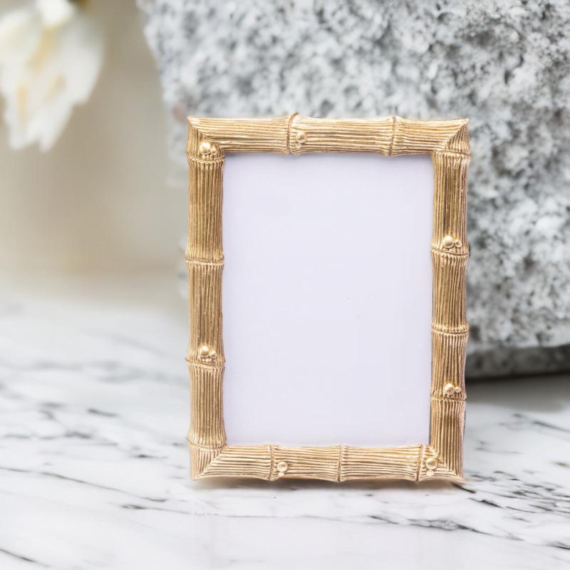 A gold bamboo wedding photo frame on a marble top.