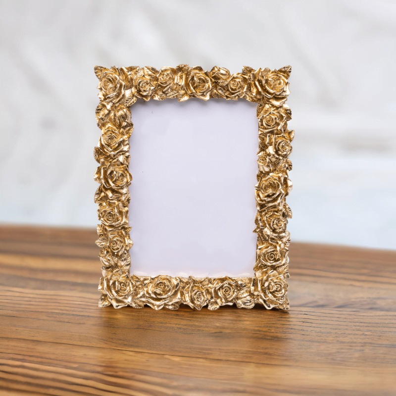 A gold rose portrait photo frame on wooden table.