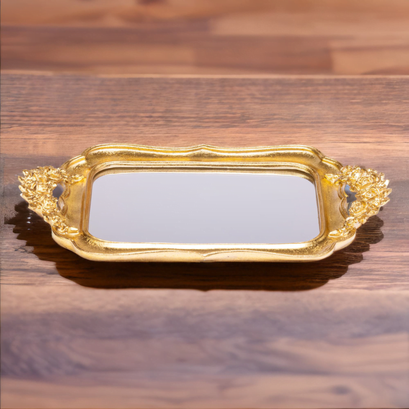 An ornate Gold Fancy Tray with mirror bottom on a wooden table.