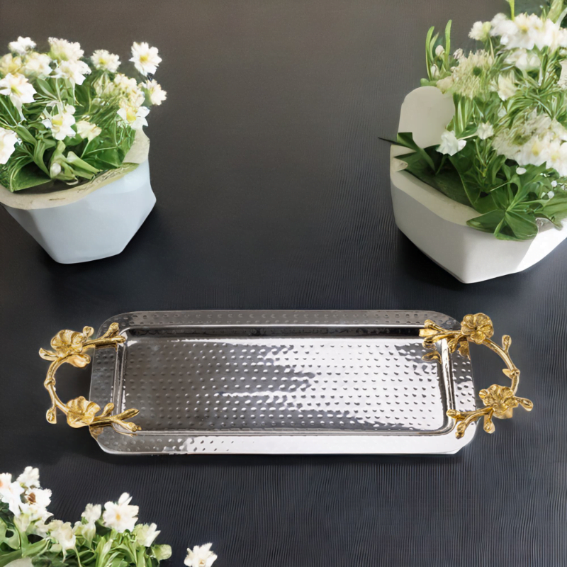 Rectangle hammered stainless steel serving tray adorned with gold handles on a table with 2 flower pots.