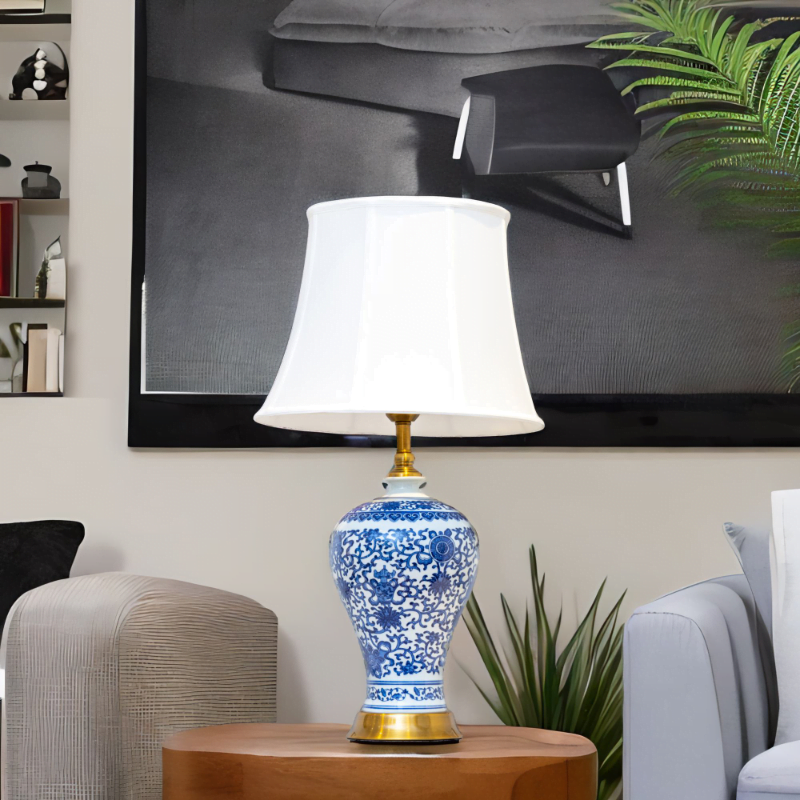 A blue and white lamp adorned with gold accents and stylish blue and white flower patterns on a side table in living room.